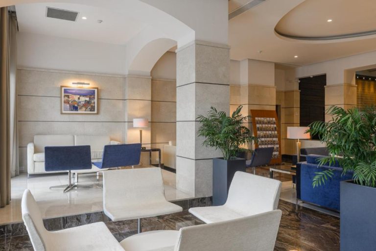 Elegante lobby del Maritim Antonine Hotel & Spa con sofás blancos y azules y plantas decorativas