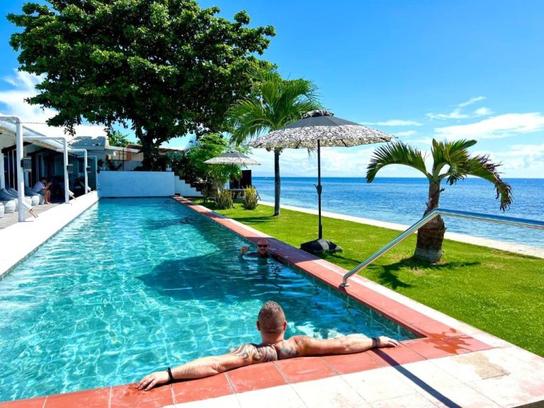 Piscina infinity con vistas al mar azul y jardín tropical en The Beachhouse Cebu, Filipinas