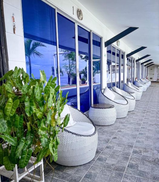 Terraza con sillas de ratán blancas y vistas al mar en The Beachhouse Cebu, Filipinas