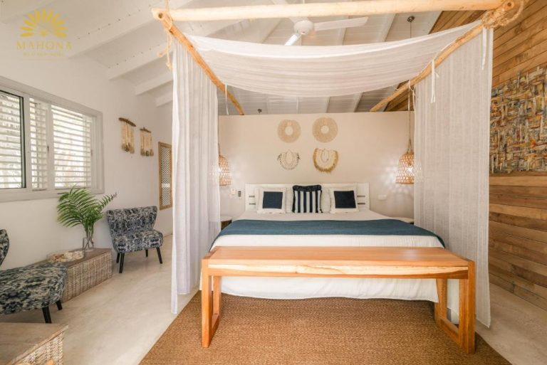 Habitación con cama dosel de madera natural y decoración tropical en Mahona Boutique Hotel