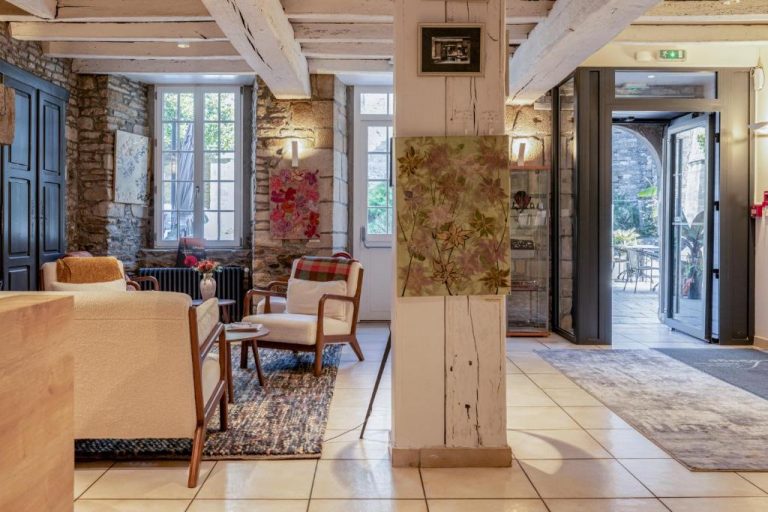 Salón lobby rústico con muros de piedra y obras de arte del Hotel Restaurant Lesage