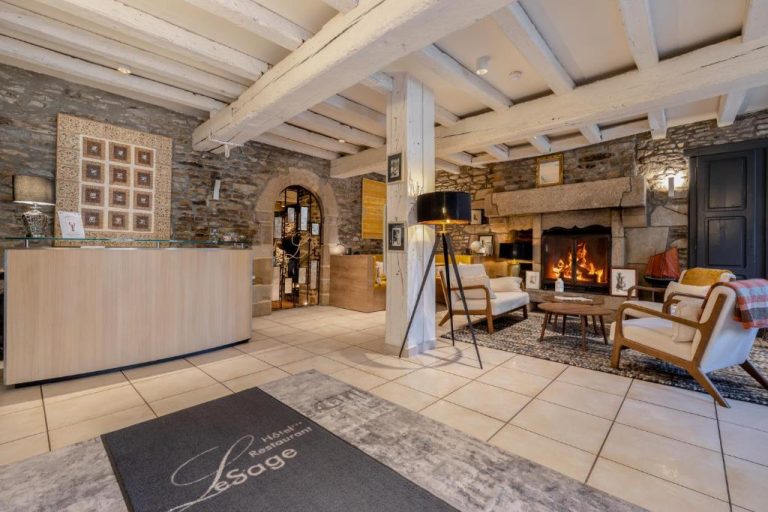 Recepción y sala de estar con chimenea de piedra encendida en el Hotel Restaurant Lesage