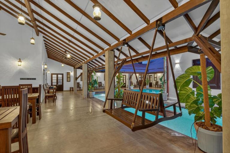Área de piscina interior con columpio de madera y zona de comedor en The Tusker's Hideout