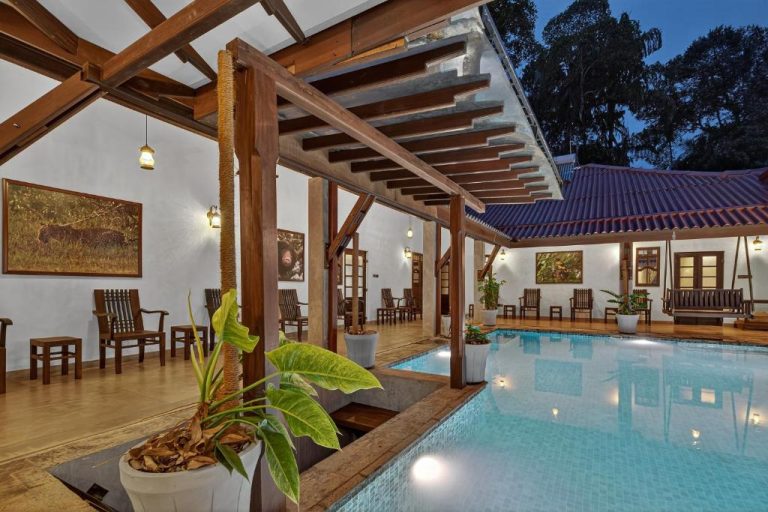 Piscina interior con pérgola de madera y terraza en The Tusker's Hideout, rodeada de vegetación tropical