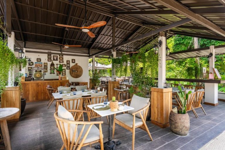 Restaurante terraza con mesas de madera y jardín tropical en Moorea Boutique Resort Samui