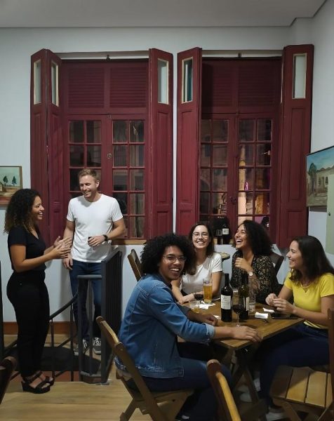 Grupo de amigos disfrutando de bebidas y risas en el área social del Hobi Hotel Boutique Bela Vista