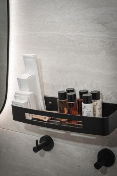 Amenities de baño de lujo con productos PRIA en estantería negra del Kentrikon 1924 Boutique Hotel