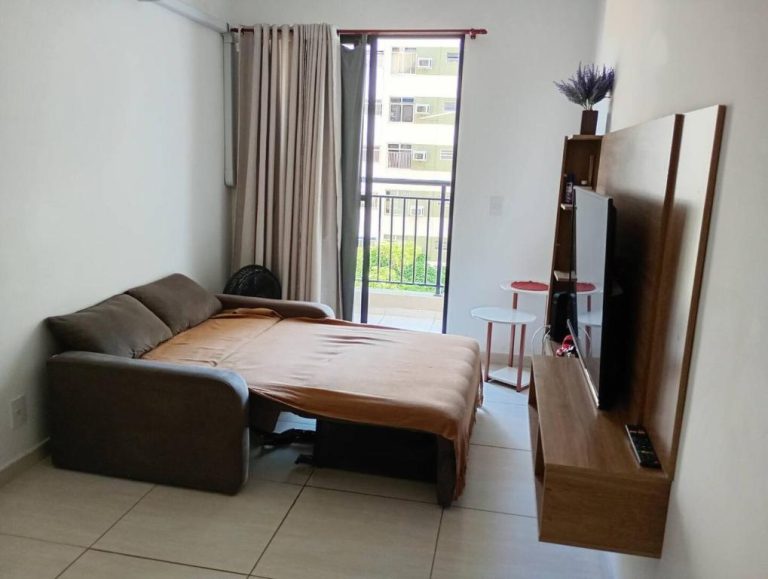 Sala de estar con sofá cama desplegado y TV en Hospedagem para Grupos, ideal para grupos