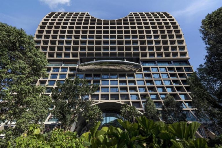 Fachada exterior del Sindhorn Kempinski Hotel Bangkok con arquitectura moderna y jardines tropicales
