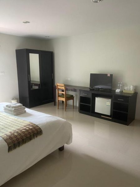 Habitación doble con cama, escritorio, televisión y armario en el hotel Baansupmongkol Krabi
