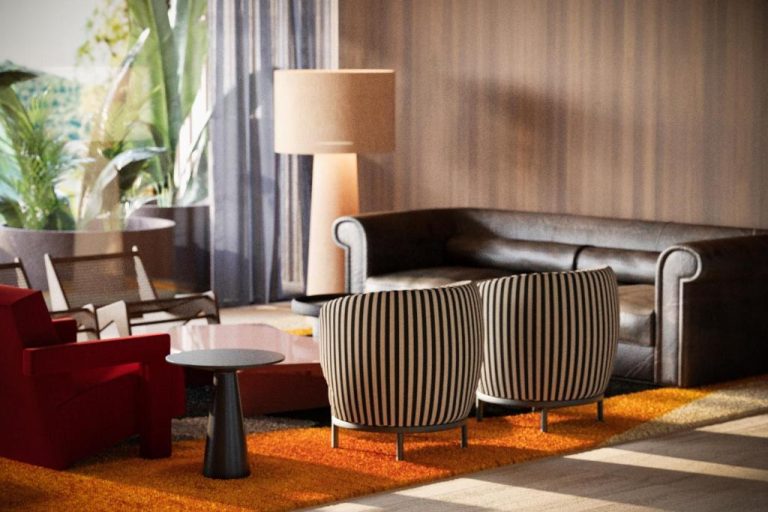 Zona de descanso del Hotel Villa Argentina con sofás a rayas, butaca roja y lámpara de pie en el lobby