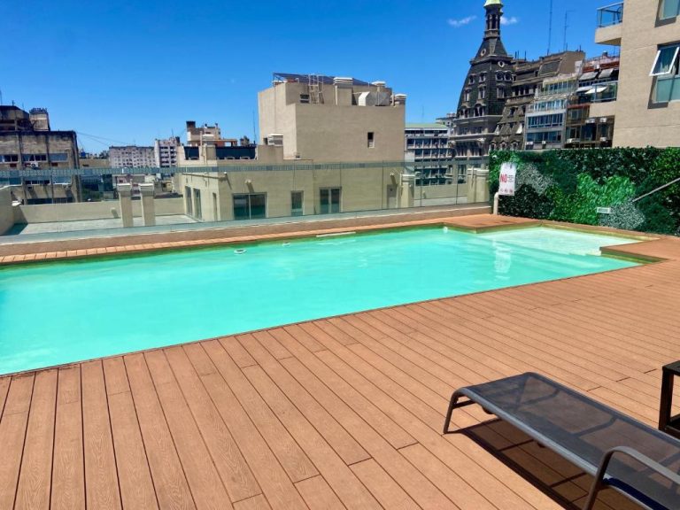 Piscina exterior en terraza con deck de madera y vistas a la ciudad en Centro Histórico Apart I