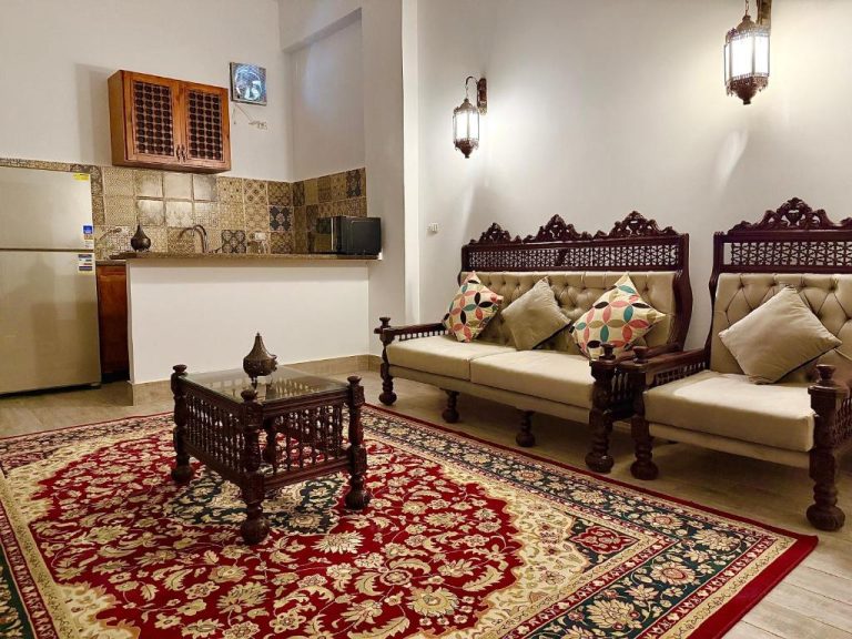 Salón de estilo árabe tradicional con sofás tallados y alfombra roja en Bab Al Shams Palace