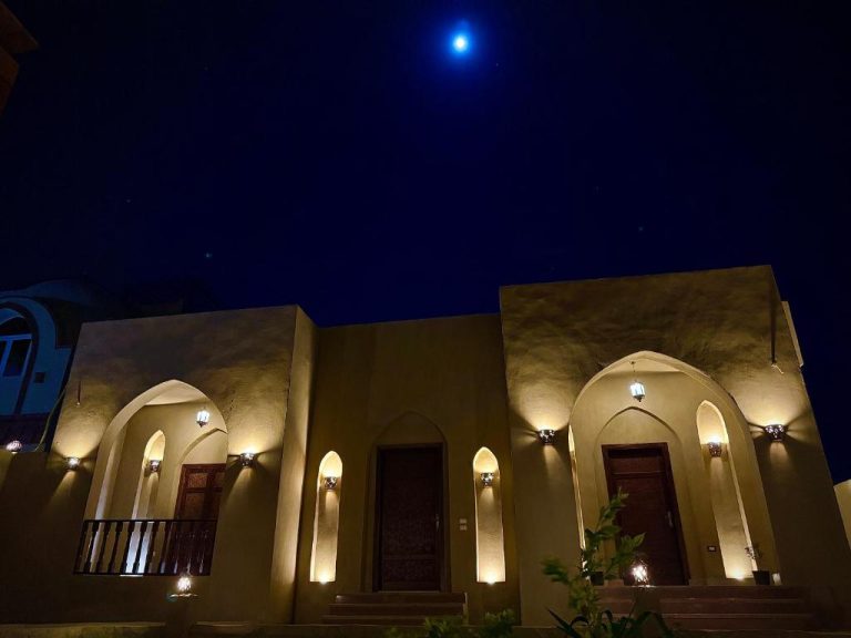 Fachada exterior iluminada de noche del Bab Al Shams Palace con arcos árabes y cielo estrellado