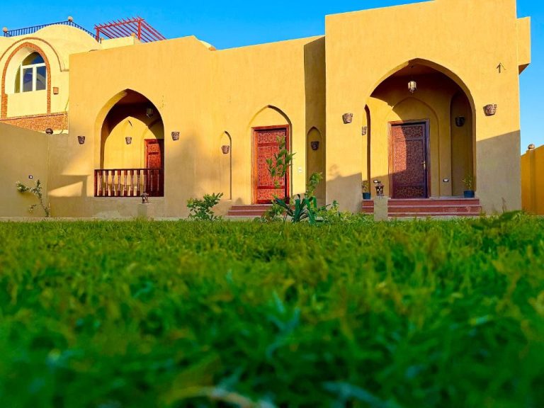Fachada exterior con arcos árabes y jardín verde del Bab Al Shams Palace en Egipto