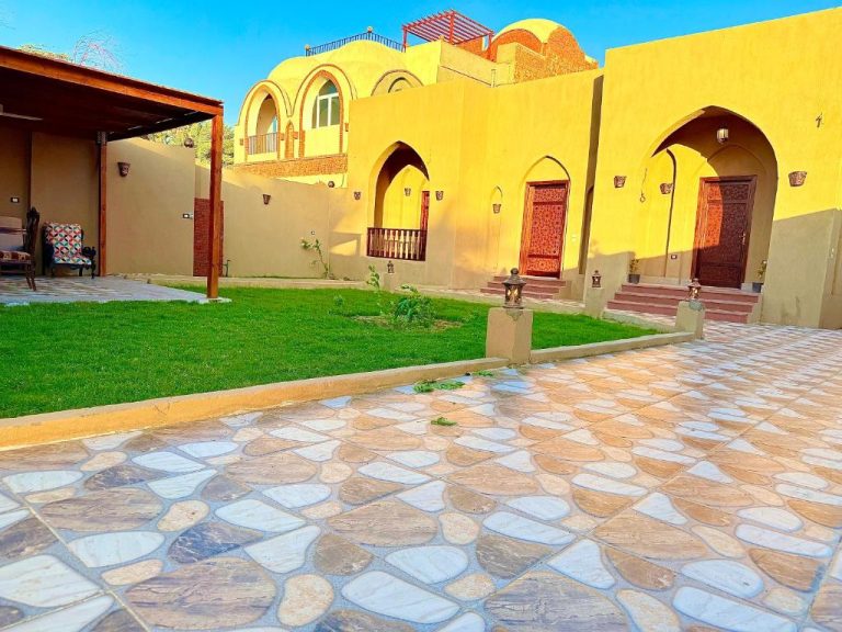 Fachada exterior con arcos árabes y jardín del Bab Al Shams Palace con pavimento de piedra