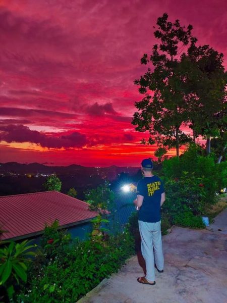 Huésped admirando el atardecer rojizo desde el mirador panorámico del SZ Samui Glamping en Koh Samui