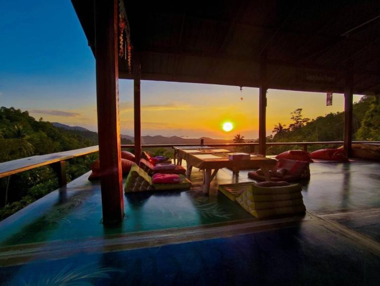Terraza con cojines y mesa baja del SZ Samui Glamping con vistas panorámicas al atardecer sobre la selva