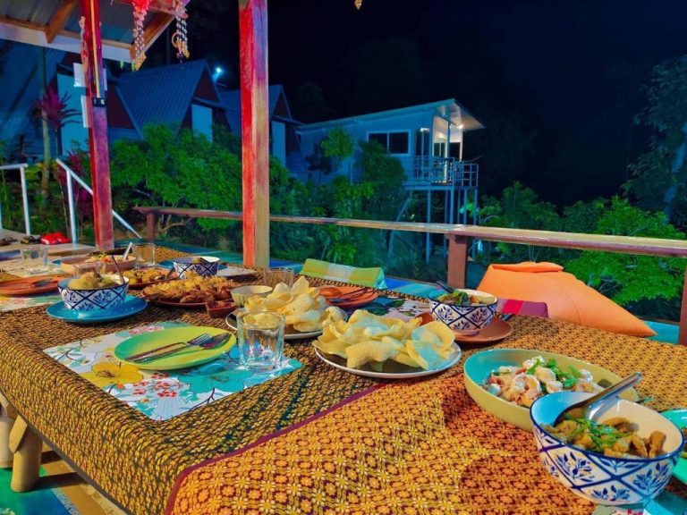 Cena tradicional tailandesa en terraza exterior nocturna del SZ Samui Glamping con vistas al jardín