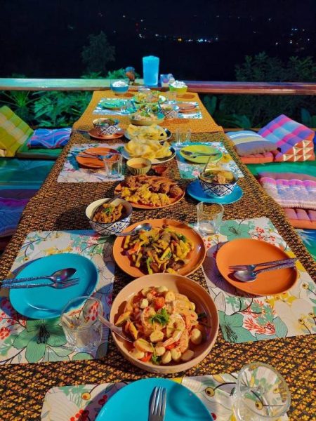 Cena tradicional tailandesa en terraza panorámica nocturna del SZ Samui Glamping con vistas al mar