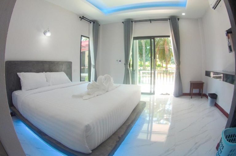 Habitación doble con cama king, suelo de mármol y balcón con vistas en PS Lanta Resort