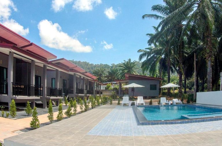 Piscina exterior con tumbonas y bungalows tropicales del PS Lanta Resort rodeado de palmeras