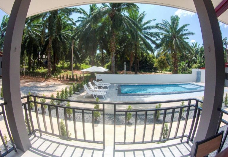 Vista desde balcón de la piscina exterior con tumbonas y sombrilla del PS Lanta Resort rodeada de palmeras