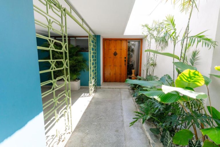 Entrada principal con puerta de madera y jardín tropical del Hotel Libreria Cafe de Pombal