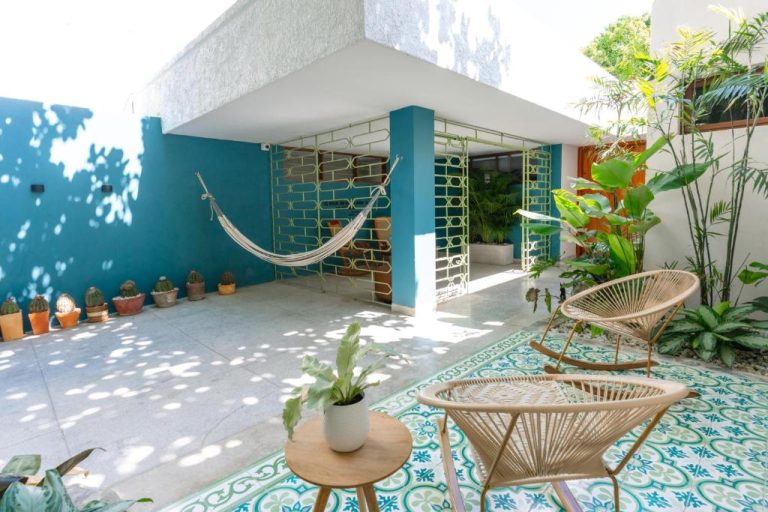 Patio exterior con hamaca, sillas Acapulco y plantas tropicales en Hotel Libreria Cafe de Pombal