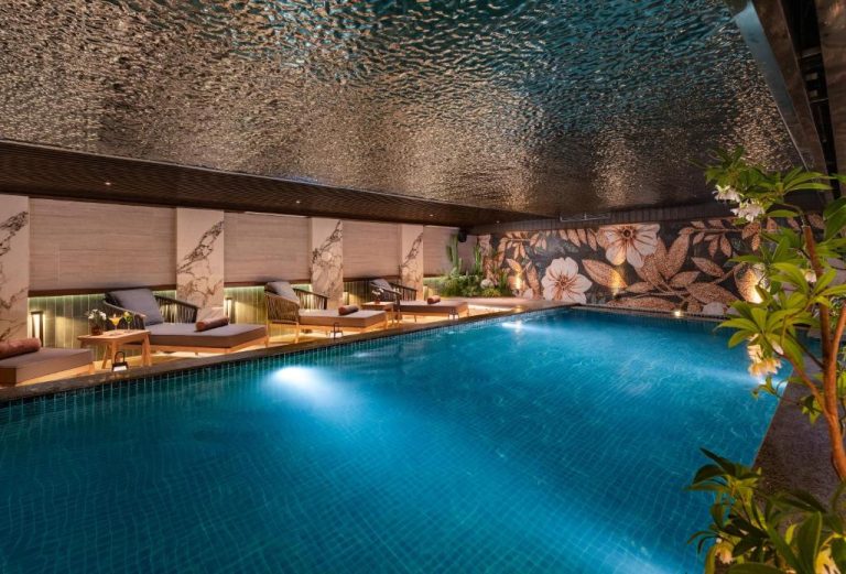Piscina interior iluminada con tumbonas y mosaico floral del Hotel du Lac Signature