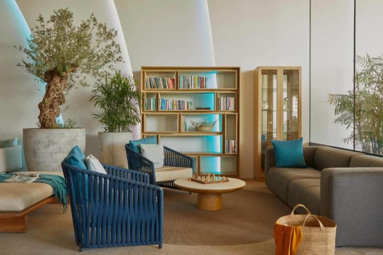 Sala de estar con librería iluminada y sillones azules en el Radisson Blu Aruba