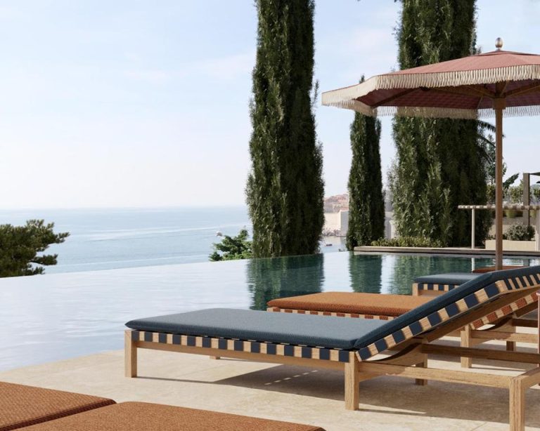 Piscina infinita con tumbonas de madera y sombrillas junto al mar en Villa Argentina