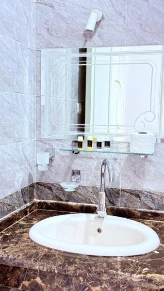 Baño de mármol con lavabo oval y espejo en el Panorama Hotel, amenities incluidos
