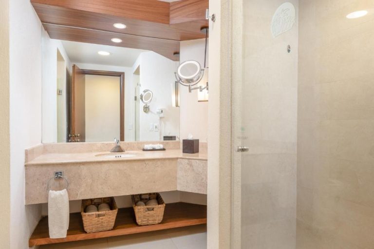 Baño moderno con encimera de mármol, espejo iluminado y ducha en Royal Solaris Los Cabos All Inclusive