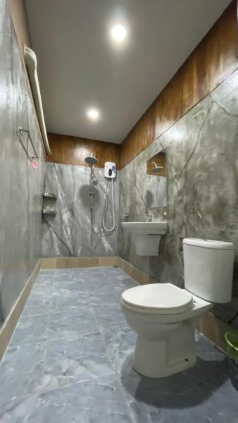 Baño completo con ducha, lavabo y aseo en Baan Gamnan Resort Krabi con paredes de cemento pulido