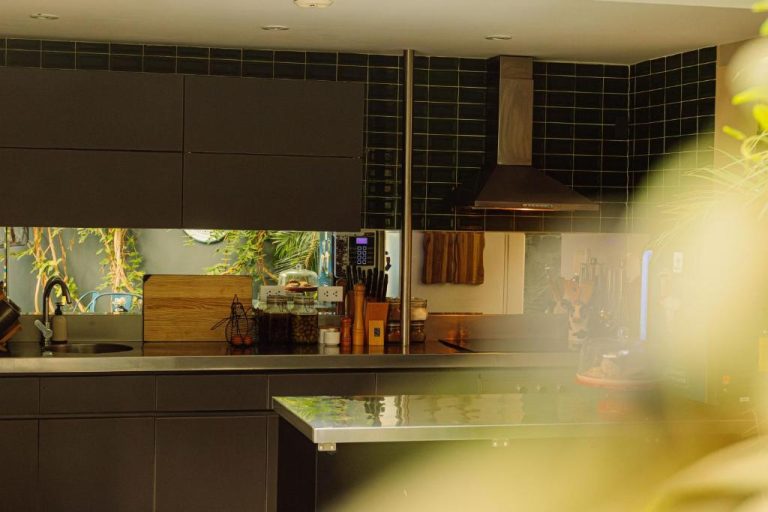 Cocina moderna con gabinetes negros, encimera de acero y azulejos oscuros en Fausto by Andean