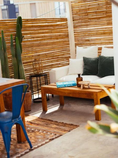 Terraza lounge exterior con sofá blanco, mesa de madera y cactus en Hotel Fausto by Andean