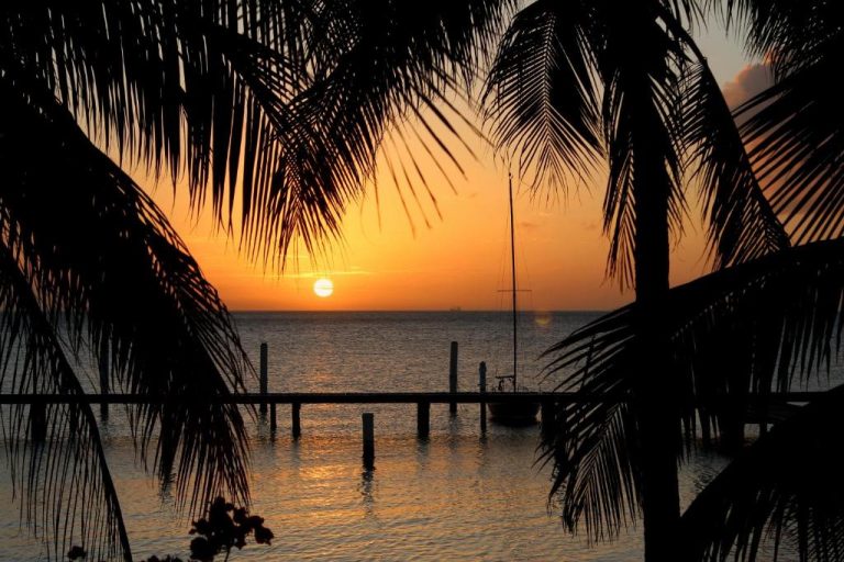 Espectacular atardecer desde el muelle del Aruba Surfside Marina con palmeras y velero al fondo