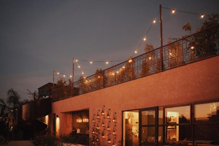 Terraza exterior iluminada con guirnaldas y faroles del The Mellah Hotel al atardecer