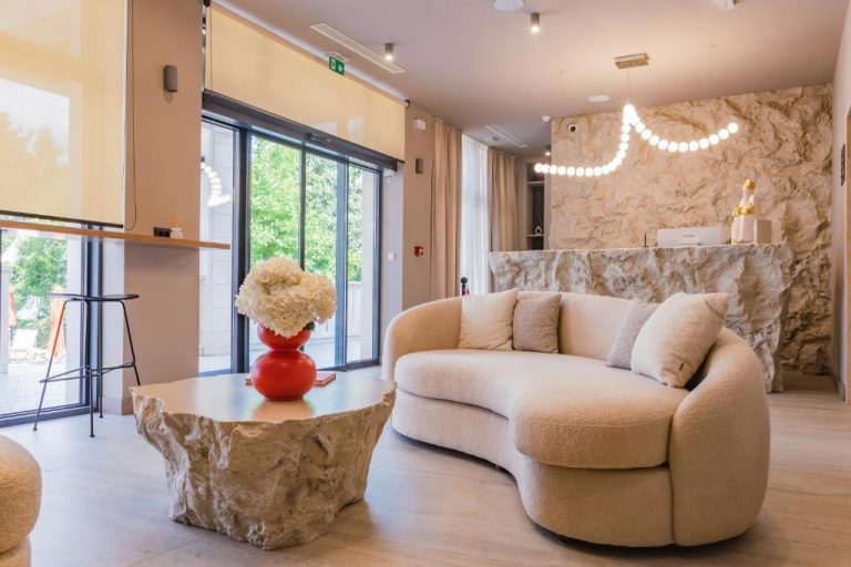 Elegante lobby del Hotel Aquarius Dubrovnik con sofá redondeado, mesa de piedra y pared de roca natural