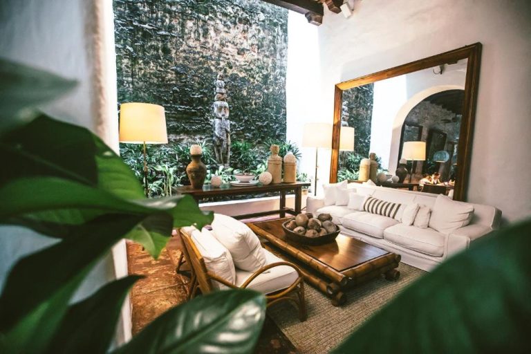 Elegante sala de estar colonial con sofás blancos y jardín interior en Amarla Boutique Hotel Cartagena