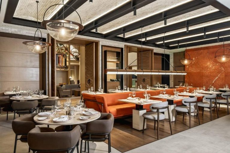 Elegante restaurante del InterContinental Real Lima Miraflores con sofás naranjas y mesas con copas de vino