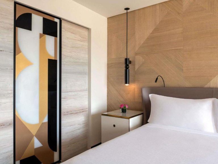Habitación de diseño moderno con cama doble y panel de madera en Rixos Gulf Hotel Doha