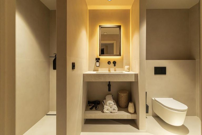 Baño moderno con lavabo de piedra y espejo retroiluminado en Wabi-Sabi Hôtel Lorrain