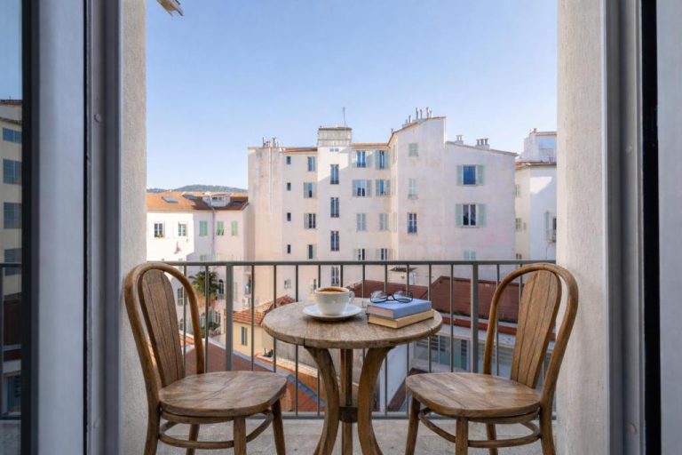 Balcón con mesa y sillas de madera y vistas a la ciudad en Wabi-Sabi Hôtel Lorrain