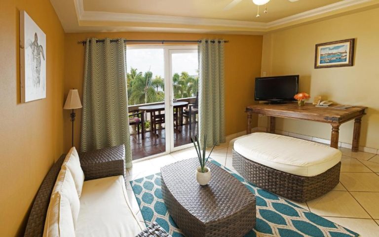 Sala de estar con terraza y vista al mar en Aruba Surfside Marina, mobiliario de ratán