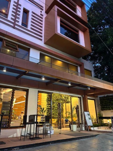 Fachada exterior iluminada del Ferra Hotel and Garden Suites con jardín vertical y terraza