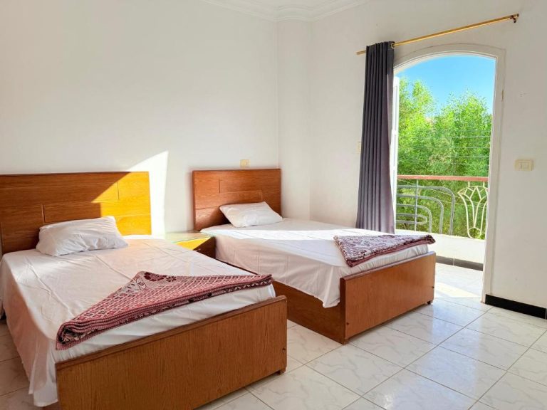 Habitación doble con dos camas y balcón con vistas al jardín en Ramla Palace House