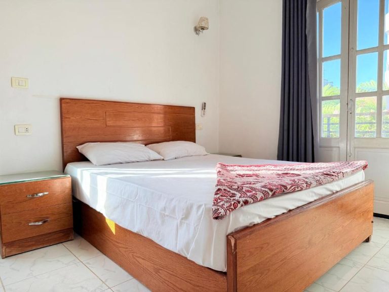 Habitación doble con cama de madera y ventana exterior en Ramla Palace House