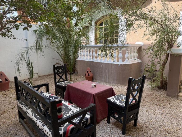 Patio exterior con mesa, sillas y jardín mediterráneo en Ramla Palace House